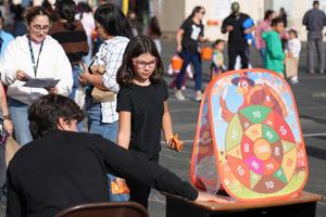 student playing beanbag toss game at harvest festival