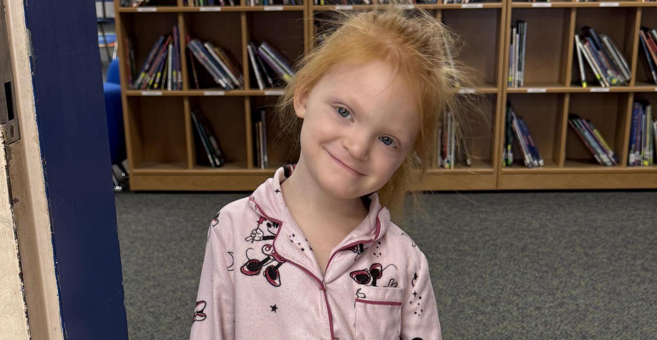 Child wearing pink pajamas with a Minnie Mouse pattern.