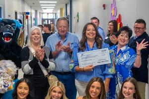 Frenship teacher and donor cheering, while holding a teacher grant check.