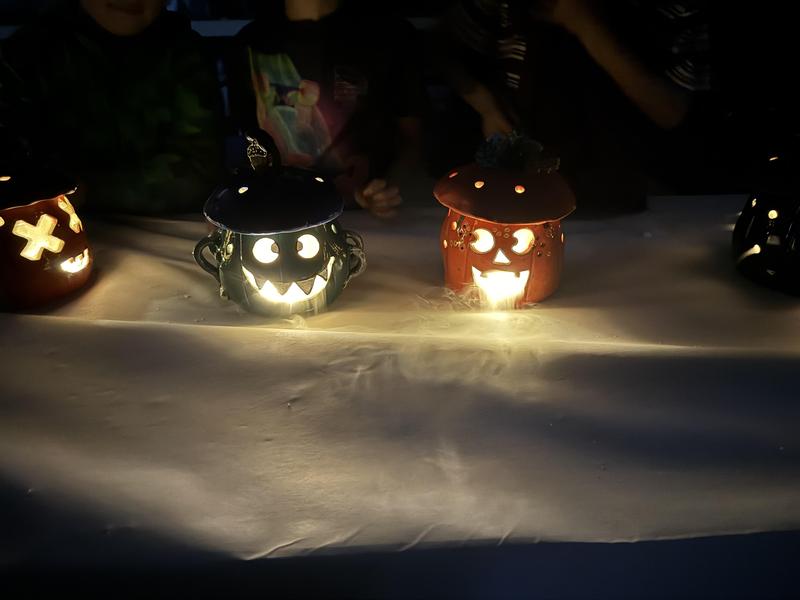 Ceramic jack-o-lanterns sitting on a table in the dark with lights inside and dry ice creating smoke coming out of the eyes and mouth.