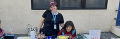 Children at a craft table with materials, decorations, and drinks during a festive event.