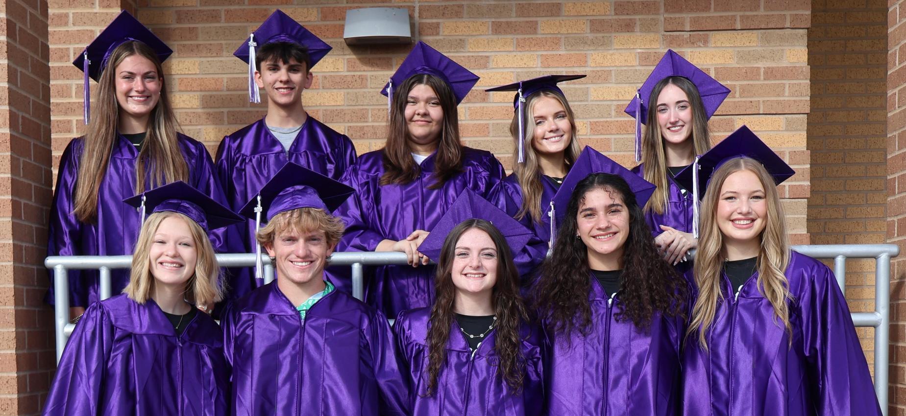 Senior class of 2026 top 10 students in their cap and gowns in front of the high school