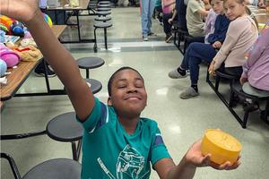 2nd-grader Denzel Nezianya holds a prize in outstretched hands and has a big smile on his face