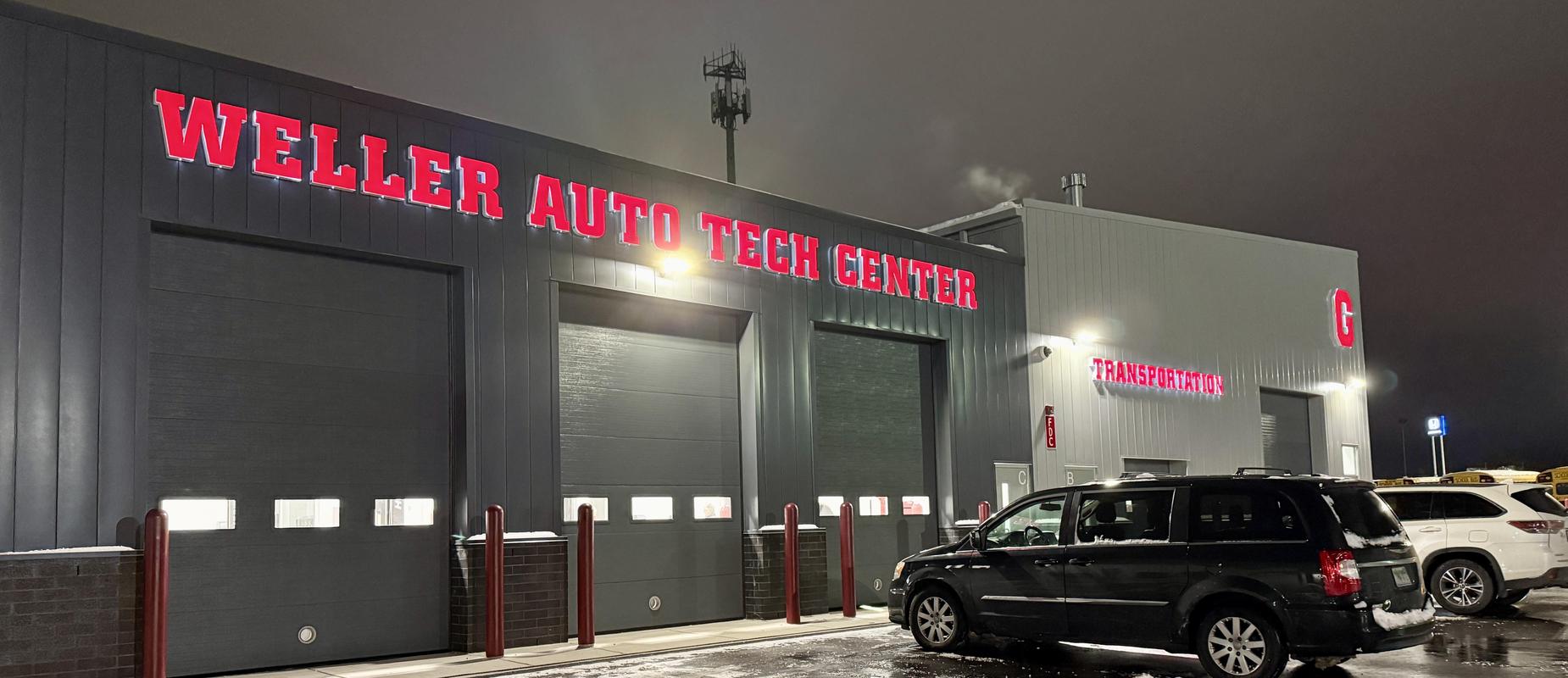 Weller Auto Tech Center exterior at night with three garages closed and cars outside