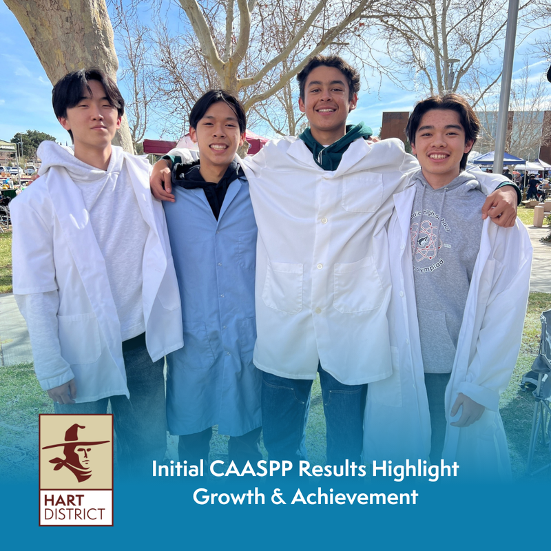 Four teen boys in white lab coats at an outdoor science fair.