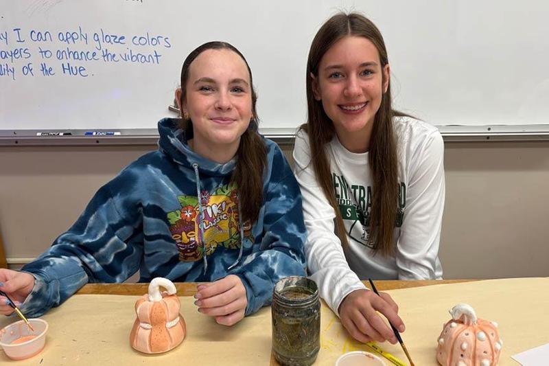 Alyssa Miller and Lily Smith paint their pumpkin sculptures