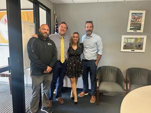 4 adults standingn in a conference room