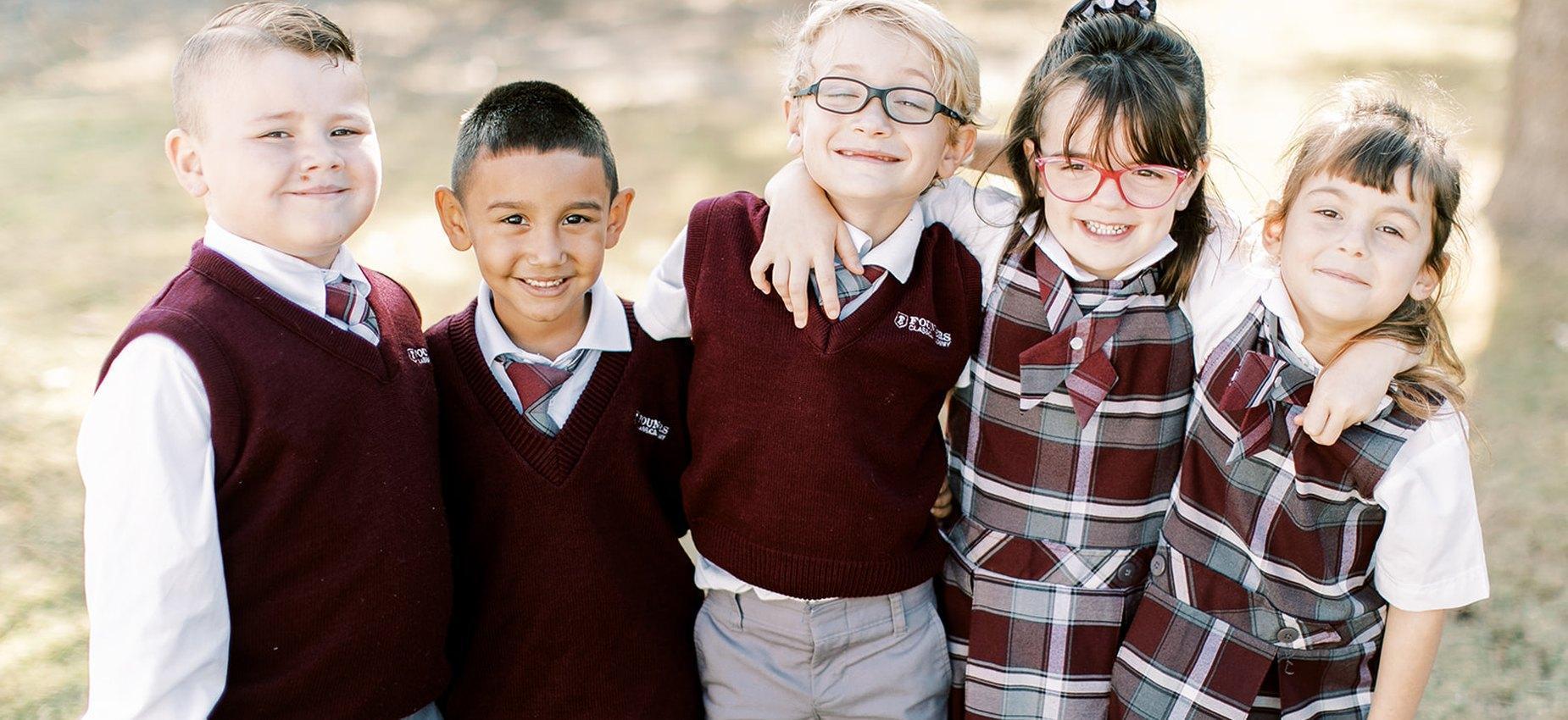 Five El Paso Classical Academy students in uniform smiling arm in arm outdoors