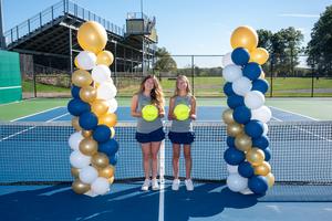 2 girls standing next to columns of balloons