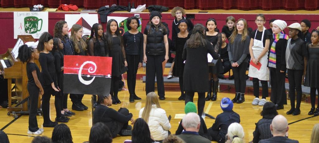 teacher directs ensemble of about twenty singing children