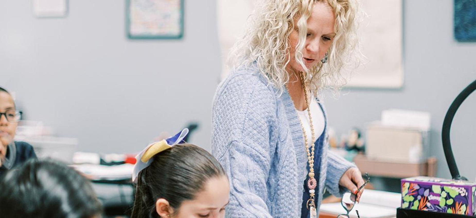 Teacher smiles while helping students in her classroom