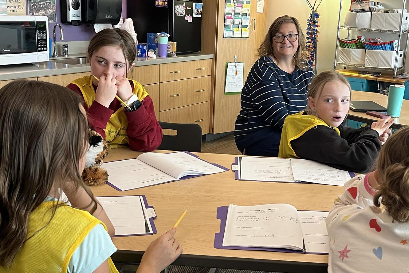 A student speaks while the teacher and other students listen.
