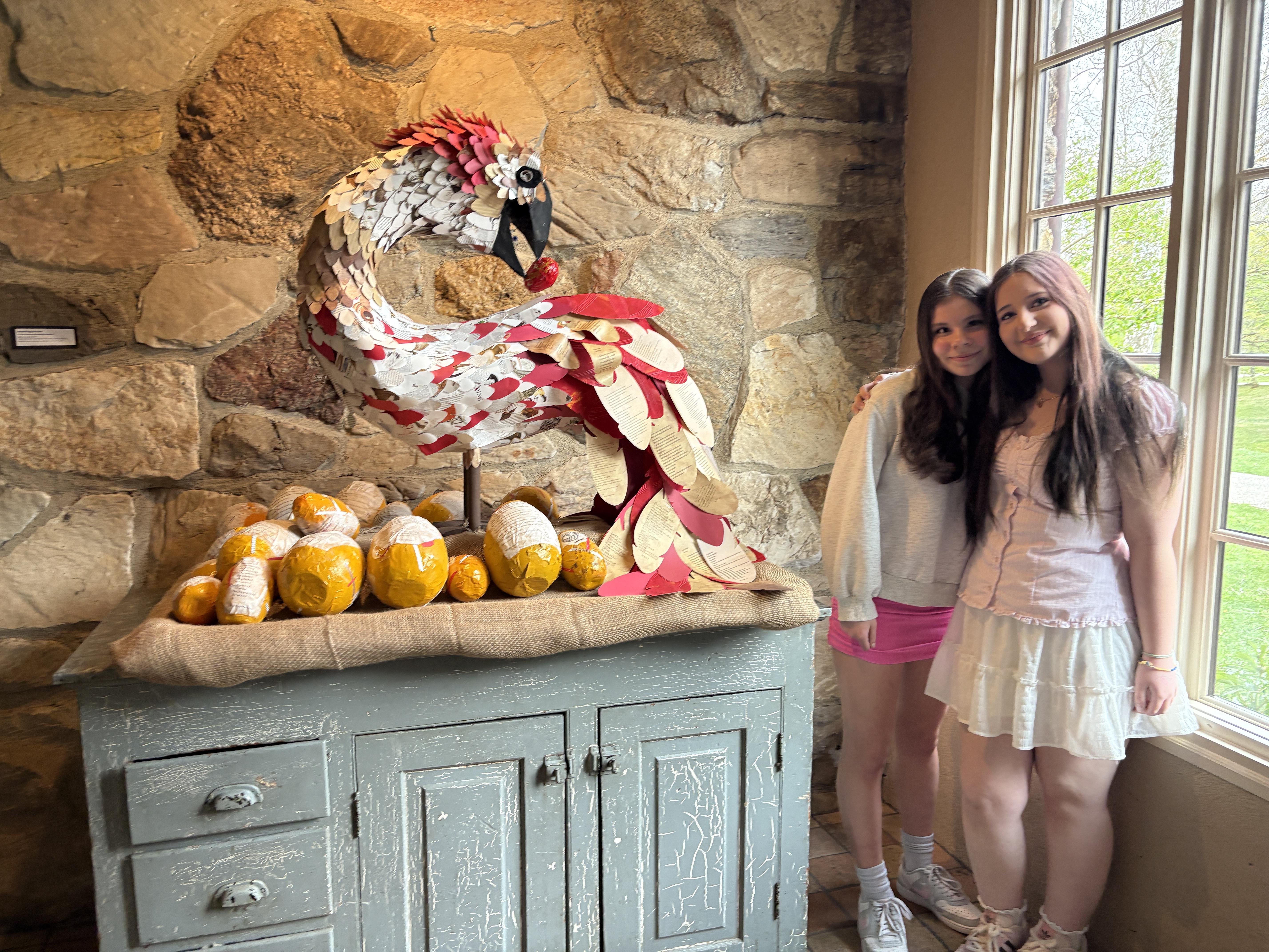 Two smiling students proudly standing next to their exhibit.