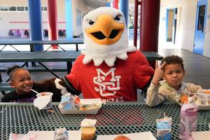 MSJC mascot, Ernie the Eagle  with two students at breakfast tables