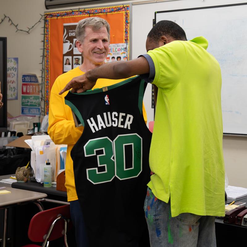 Smiling man holding a basketball jersey with the name Hauser and number 30.