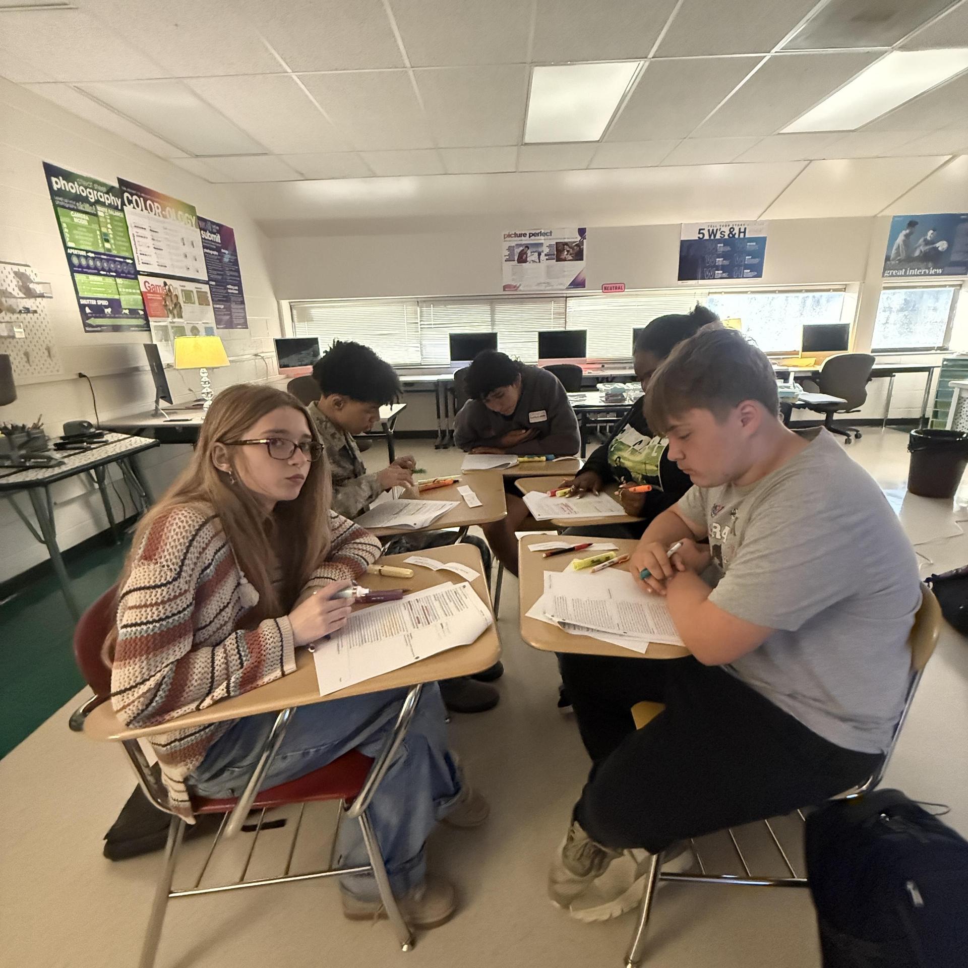 Group of students focused on their schoolwork at a table in a classroom.
