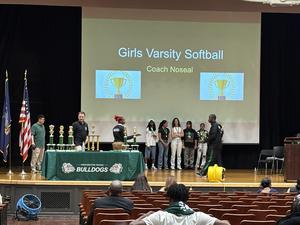 Girls varsity softball awards ceremony featuring team in front of trophies.