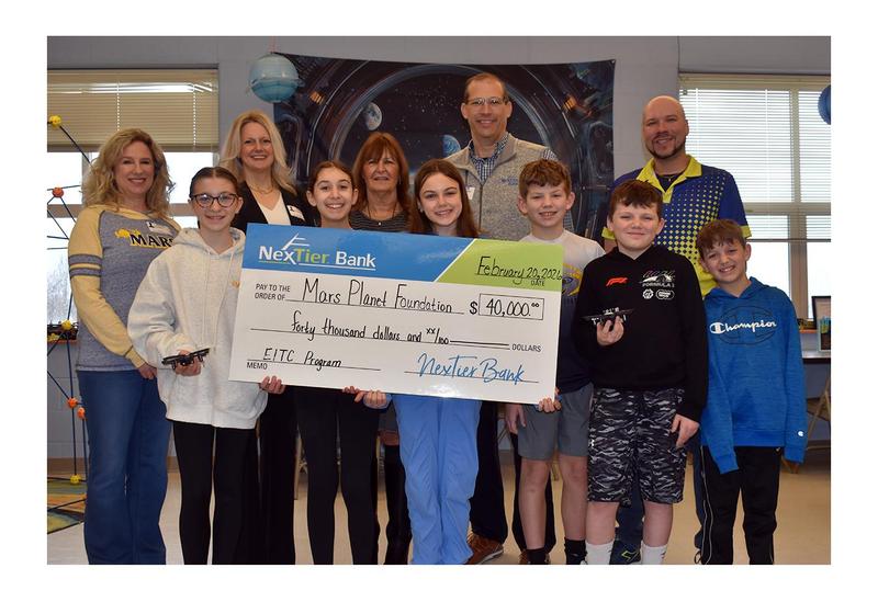 a group of adults and children holding a large paper check.