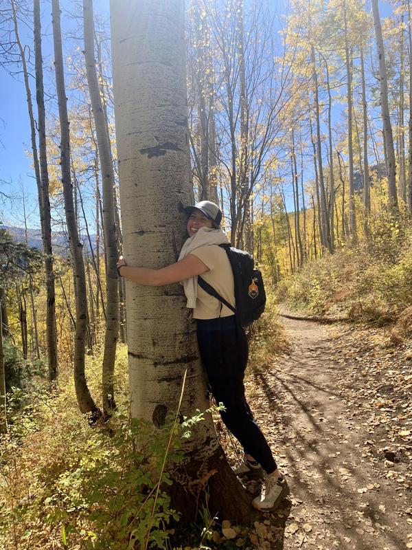 Tori Simpson hugs a tree on a hike