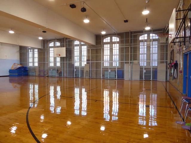 An empty gymnasium with polished wooden floors and basketball hoops.