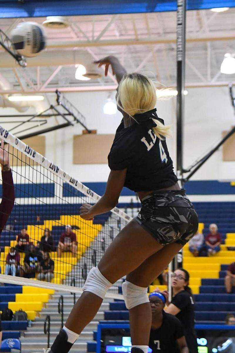 Volleyball player hitting ball over net