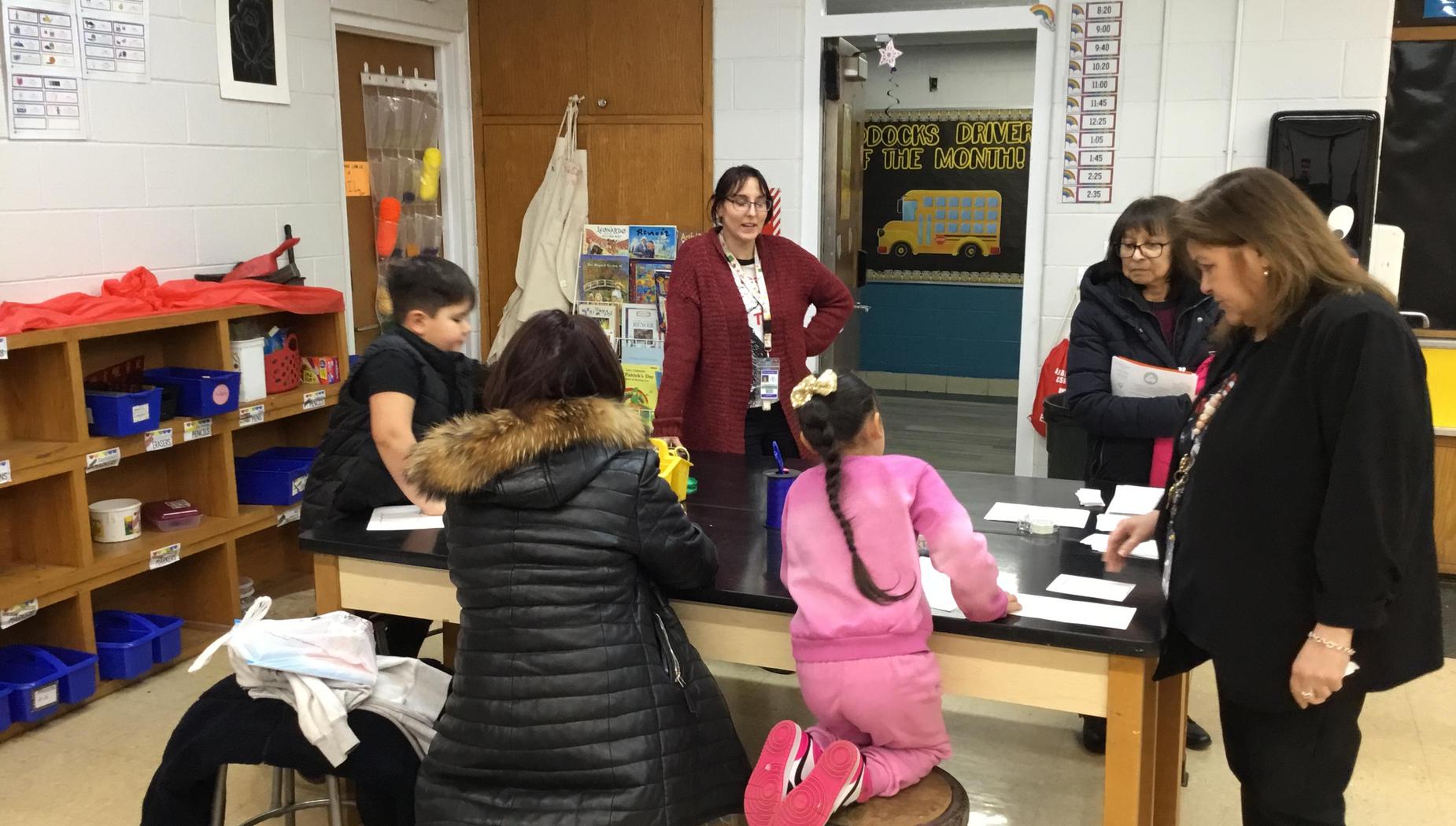 A classroom scene with children and adults engaging at a table.