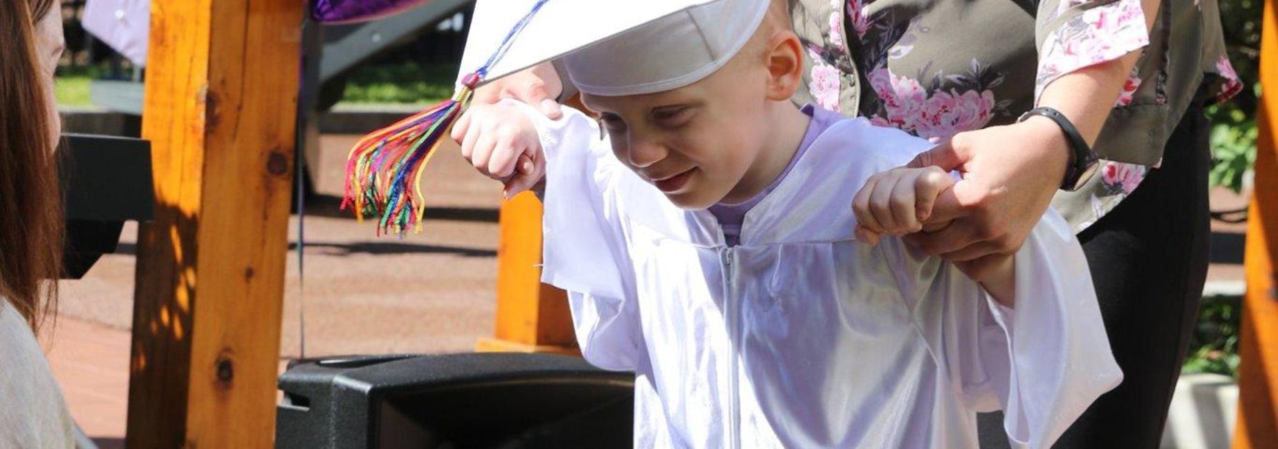 student accepting his preschool graduation diploma
