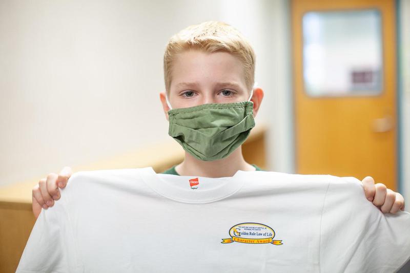 boy holds up white shirt