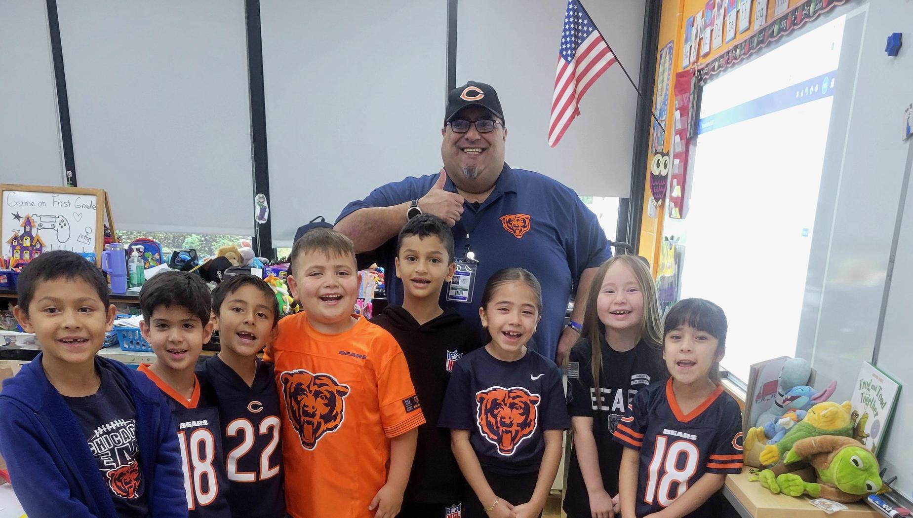 Group of children wearing Chicago Bears jerseys, smiling in a classroom setting.