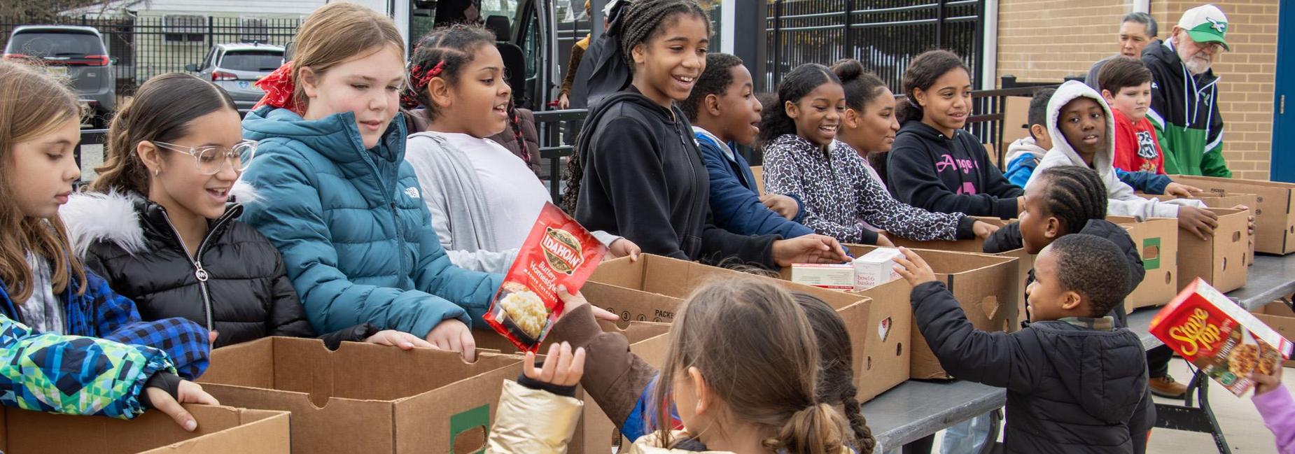 Children working together at a table filled with cardboard boxes.