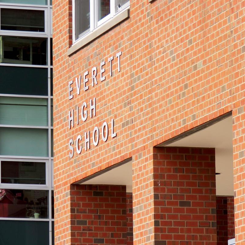 Close crop of the exterior of a red-brick school, and the lettering that reads 'Everett High School'