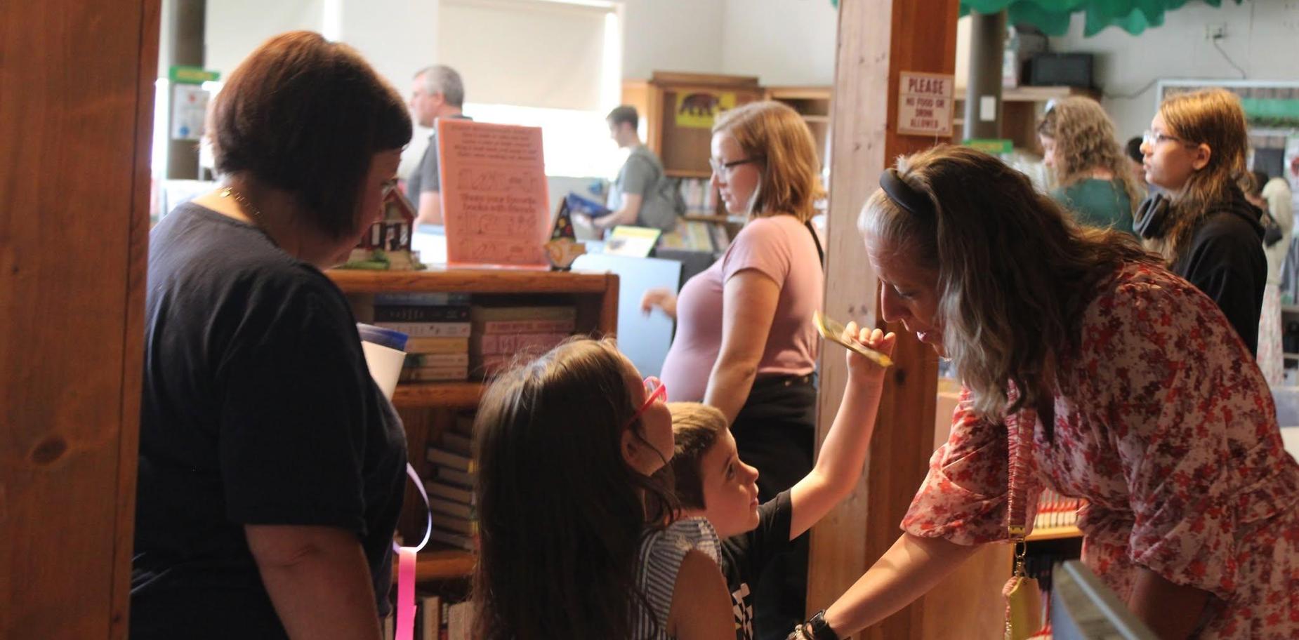 Adults and children engaging at a community event in a library.