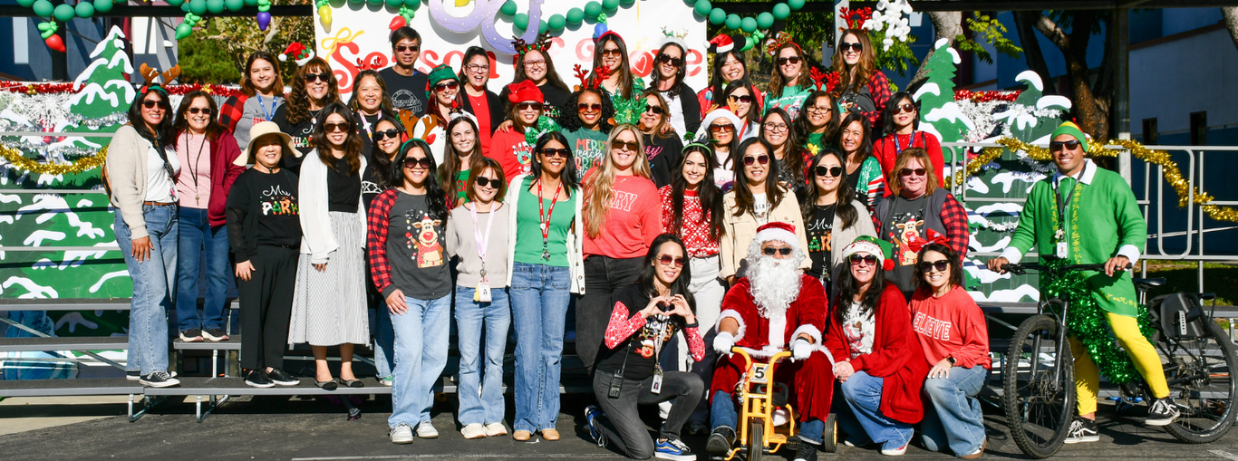 Large group of adults and Santa in festive attire, celebrating together with decorations.