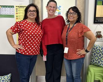 Three women in matching red outfits smiling at the camera.