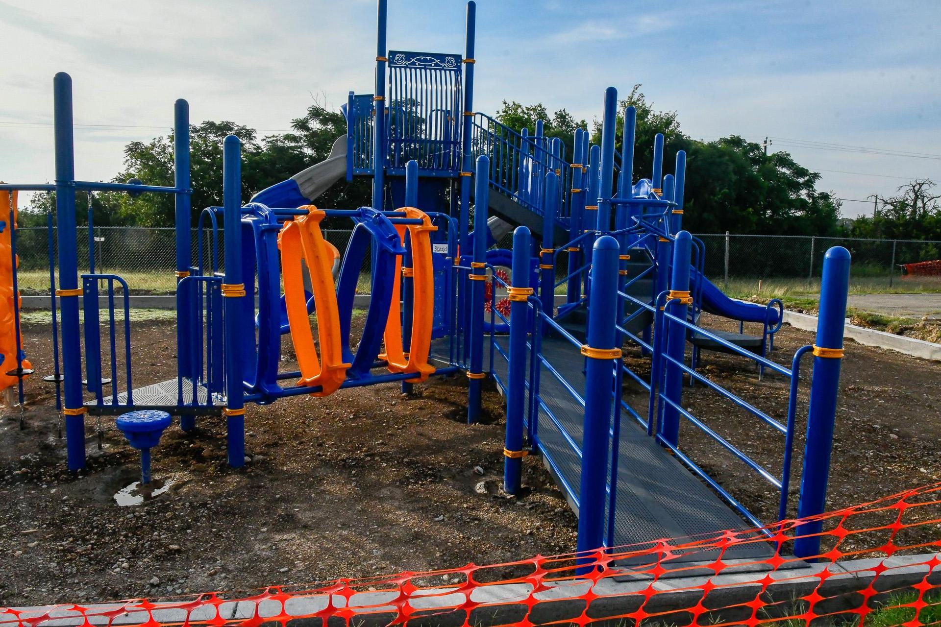 View of a playground with slides and a suspension bridge.