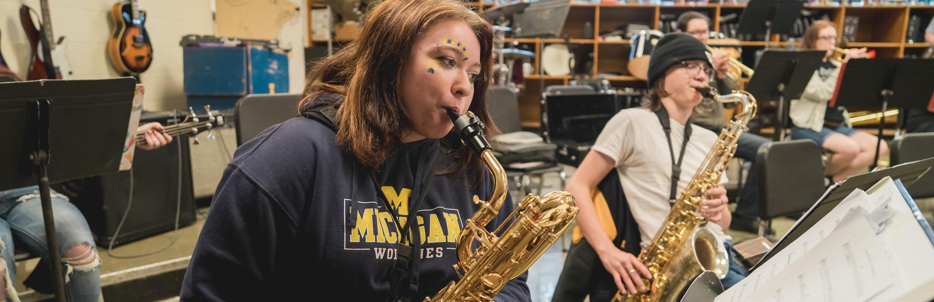 Musicians playing saxophones in a band practice setting.