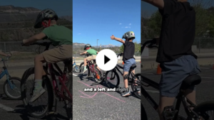 2nd graders practice a left-turn hand signal while riding bikes on a safety course