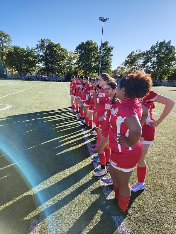 girls on the soccer team standing next to one another in their uniforms on the soccer field