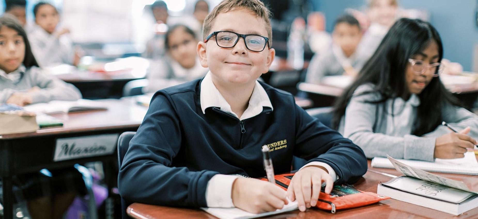 Smiling student with glasses works at his desk