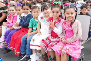 students in cultural dress sitting on a bench.