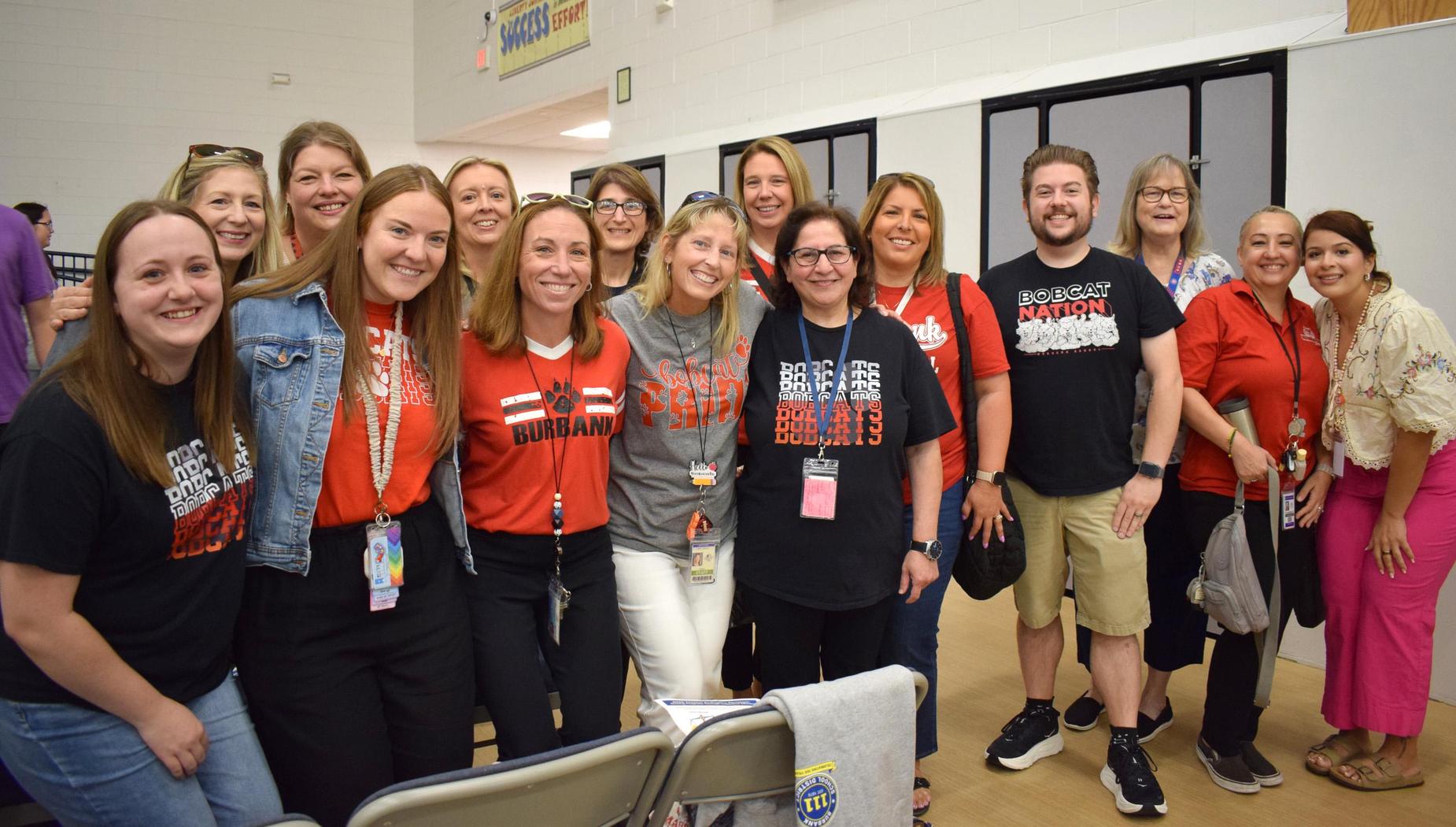 Large group of people in red and black shirts, smiling at a community event.