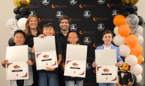 group photo of students holding awards in front of black and orange balloon backdrop