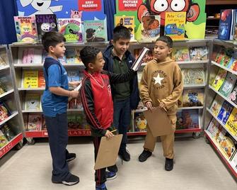 4 boys atanding and looking at books in book fair carts