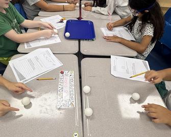 Children participating in a hands-on experiment with balls on tables.
