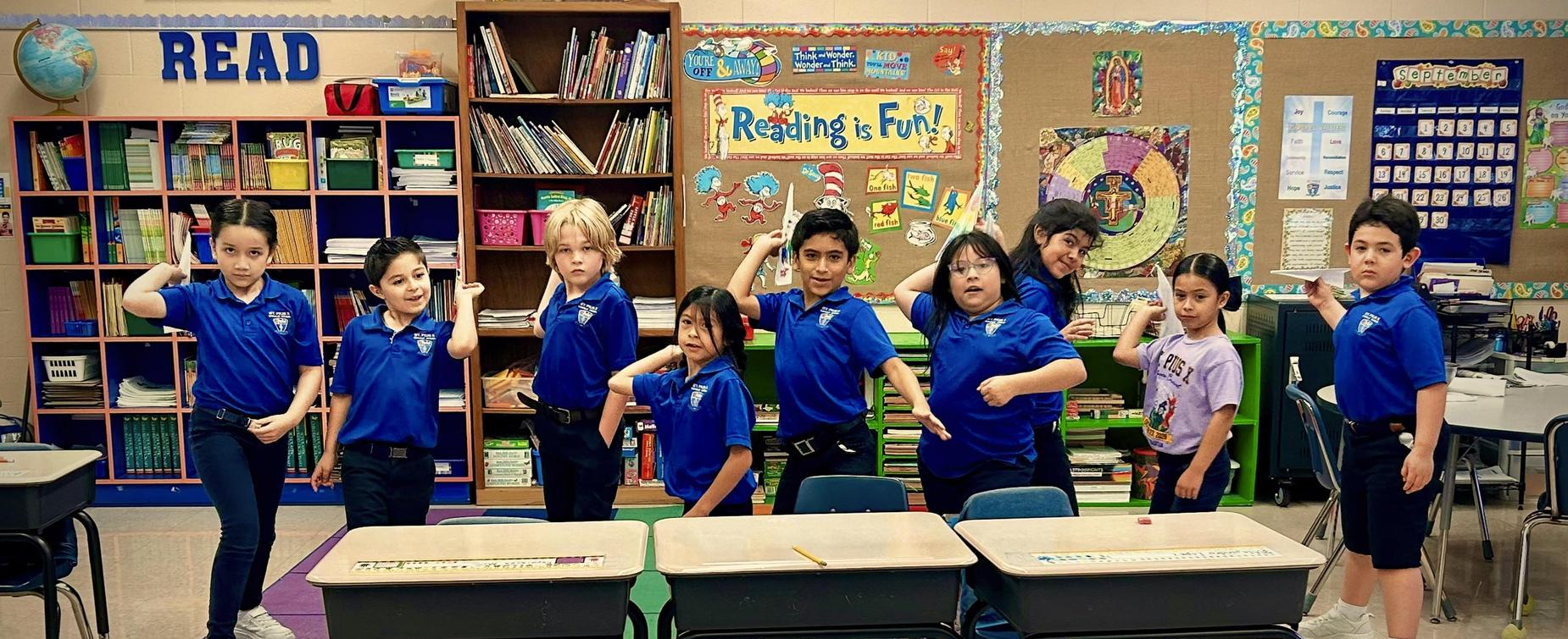 A diverse group of children posing playfully in a classroom setting.