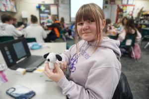 A student holds up a miniature Snoopy figure she crocheted.