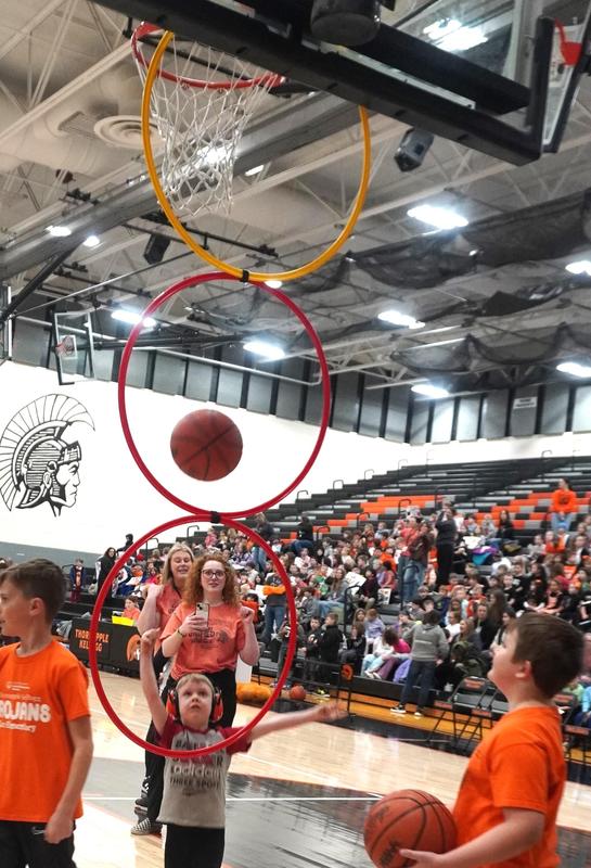 A student shoots the basketball through one of three hoops hung from the basketball rim.