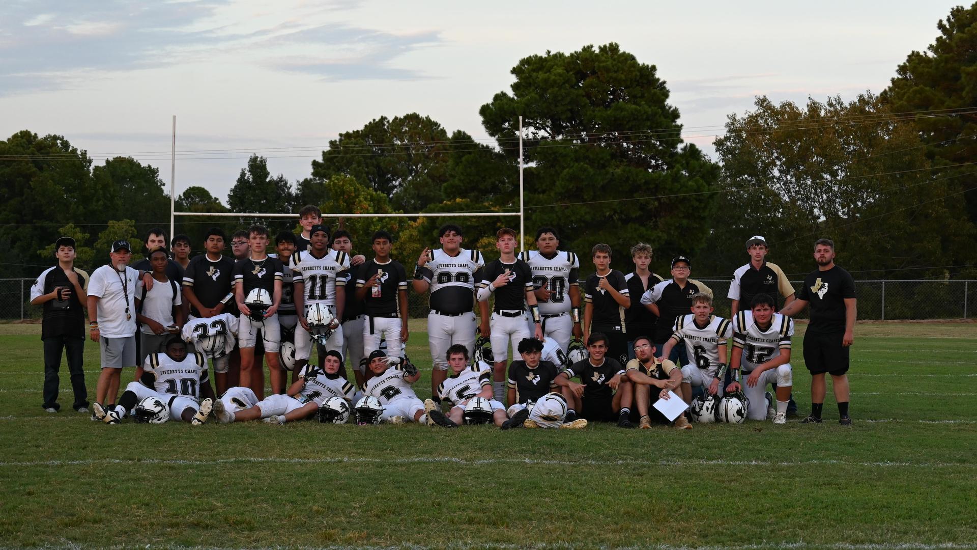 A group of football players posing together on a grassy field.