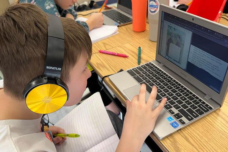 Fifth-grader Luke Sakowski wears headphones while completing comprehension questions