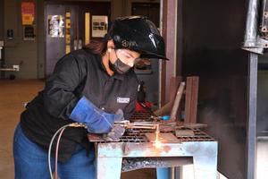 Pictured is Kayla Garza torching metal.